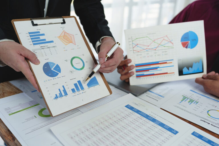 Two,Colleagues,Analyzing,Financial,Data,Reports,On,Laptop,With,Charts